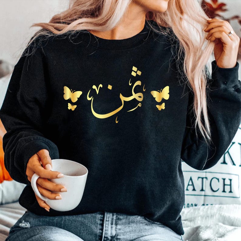 Personalised Arabic Calligraphy Sweatshirt featuring elegant butterfly artwork and custom Arabic name design. Premium unisex sweatshirt personalised with your chosen Arabic text, combining Islamic calligraphy, modest fashion, and meaningful personalised clothing. Designed for comfort and style, this Arabic sweatshirt is perfect for everyday wear, family gatherings, special occasions, and women who appreciate faith-inspired fashion with a personal touch.