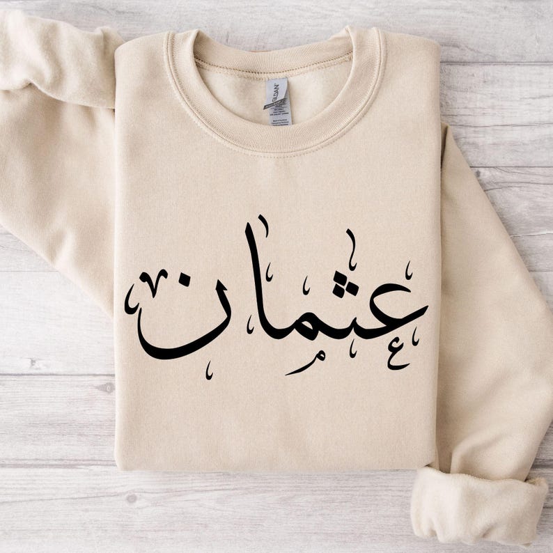 Personalised Arabic Calligraphy Sweatshirt featuring elegant Arabic typography and meaningful Islamic-inspired styling. Customised with your chosen Arabic name or text, this premium sweatshirt reflects faith, identity, culture, and personal expression through beautiful Arabic script. Perfect for Muslim women seeking modest fashion, personalised Islamic clothing, faith-based apparel, and stylish everyday wear that combines comfort, elegance, and spiritual significance in one timeless design.