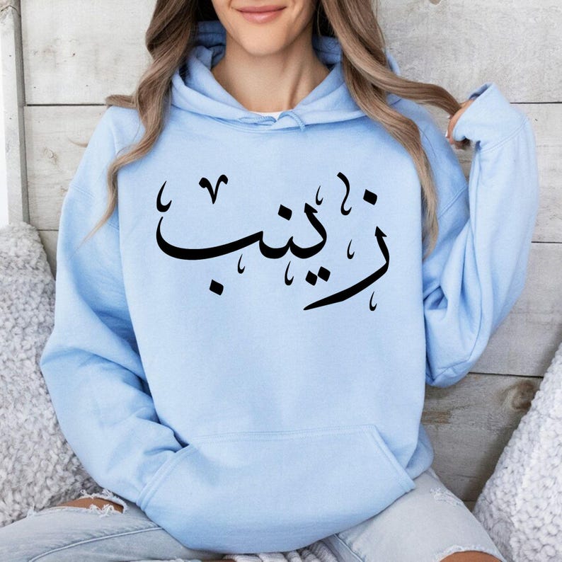 Personalised Arabic Name Hoodie combines modern Arabic typography, personalised fashion, and everyday comfort in one stylish garment. Perfect for casual streetwear, modest fashion styling, travel outfits, family gatherings, social occasions, shopping trips, coffee dates, and daily wear. This premium personalised hoodie celebrates culture, identity, and individuality through elegant Arabic calligraphy and contemporary fashion design. Ideal for customers seeking personalised Arabic clothing, custom name hoodi