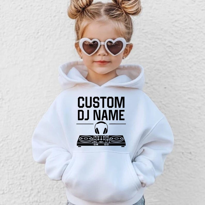 Create a unique personalised Kids DJ Hoodie by adding your child's custom DJ name above the stylish controller design. An ideal gift for boys and girls who enjoy music, dancing and performing. Great for birthdays, Christmas, special occasions and everyday outfits. Every hoodie is made to order and professionally printed in the UK by TeezoraPrints for premium quality and lasting comfort.