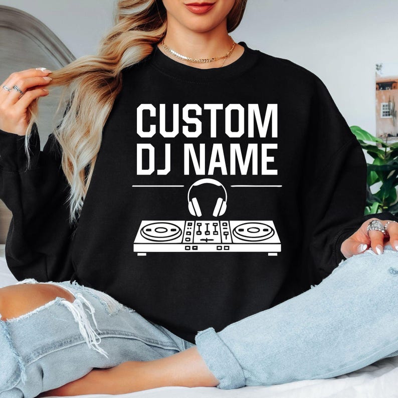 Designed for DJs, music producers, festival performers and electronic music lovers, this personalised sweatshirt features a custom DJ name above a professional controller and headphones graphic. Perfect for performances, studio sessions and everyday outfits. Every premium crewneck is professionally printed in the UK by TeezoraPrints using high-quality materials.