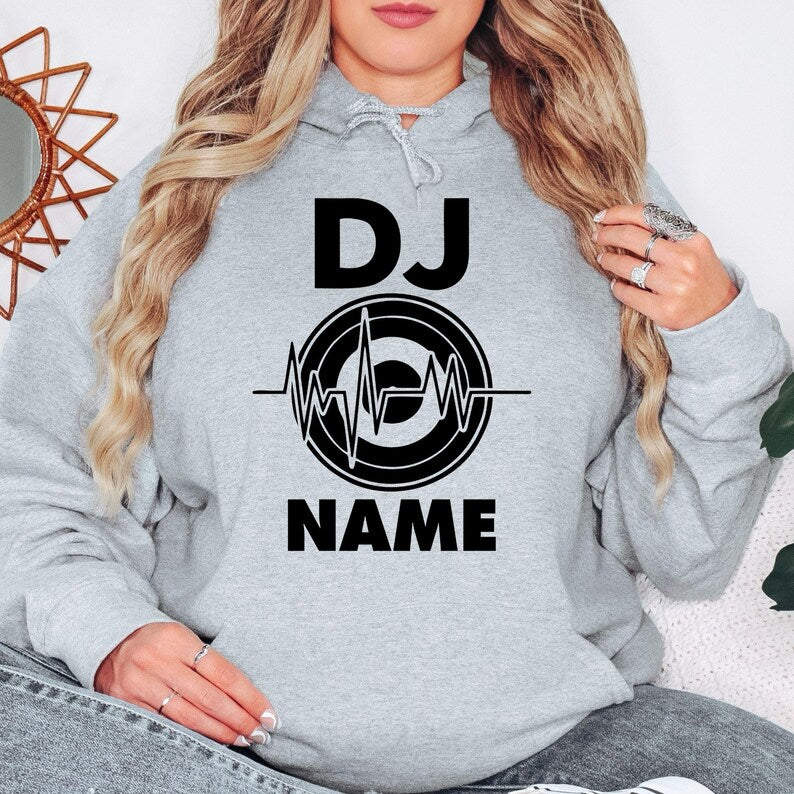 Celebrate your passion for DJ culture with this personalised hoodie showcasing a custom name and stylish heartbeat turntable artwork. Ideal for club performances, festivals, studio work and casual wear. Every premium hoodie is professionally printed in the UK by TeezoraPrints.