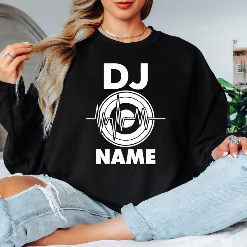 Designed for DJs, producers, festival performers and electronic music fans, this personalised sweatshirt features a custom DJ name with a heartbeat turntable graphic. Ideal for performances, studio sessions and everyday outfits, every premium crewneck is professionally printed in the UK by TeezoraPrints using high-quality fabric for lasting comfort and durability.