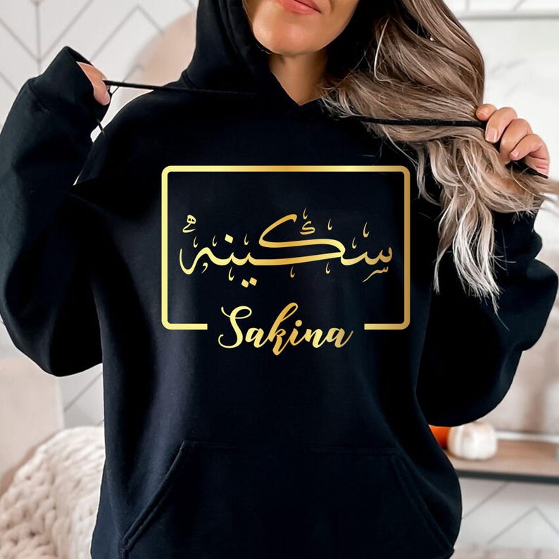 Personalised Arabic Name Hoodie created for Muslim women, Arabic culture enthusiasts, and anyone who appreciates meaningful personalised fashion. This stylish black hoodie features a custom Arabic calligraphy name design printed in elegant gold, creating a sophisticated and unique look. Perfect for daughters, sisters, wives, mothers, and friends who want to express identity, culture, and individuality through premium personalised clothing suitable for everyday wear and special occasions.