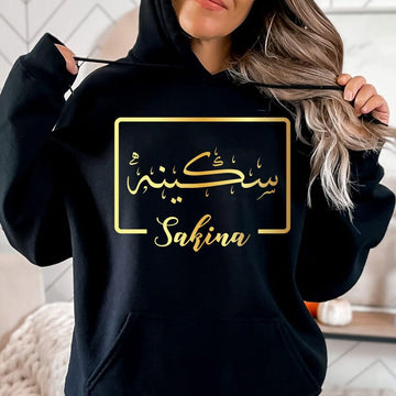 Personalised Arabic Name Hoodie created for Muslim women, Arabic culture enthusiasts, and anyone who appreciates meaningful personalised fashion. This stylish black hoodie features a custom Arabic calligraphy name design printed in elegant gold, creating a sophisticated and unique look. Perfect for daughters, sisters, wives, mothers, and friends who want to express identity, culture, and individuality through premium personalised clothing suitable for everyday wear and special occasions.