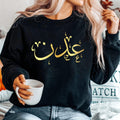 Personalised Arabic Calligraphy Sweatshirt featuring elegant Arabic typography and custom name design. Premium unisex sweatshirt personalised with your chosen Arabic text, combining Islamic-inspired fashion, meaningful personalised clothing, and timeless style. Designed for everyday comfort and modern modest wear, this Arabic sweatshirt offers a stylish and elegant look suitable for family gatherings, casual outings, special occasions, and year-round fashion.