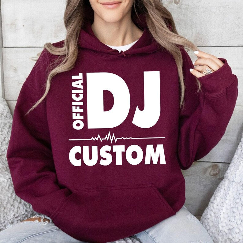 Create your own personalised Official DJ Heartbeat Hoodie by adding any name beneath the bold DJ design. Featuring a stylish heartbeat waveform and premium-quality fabric, this hoodie offers warmth, comfort and standout style for DJs, producers and music lovers. Professionally printed in the UK by TeezoraPrints with vibrant, long-lasting print quality.
