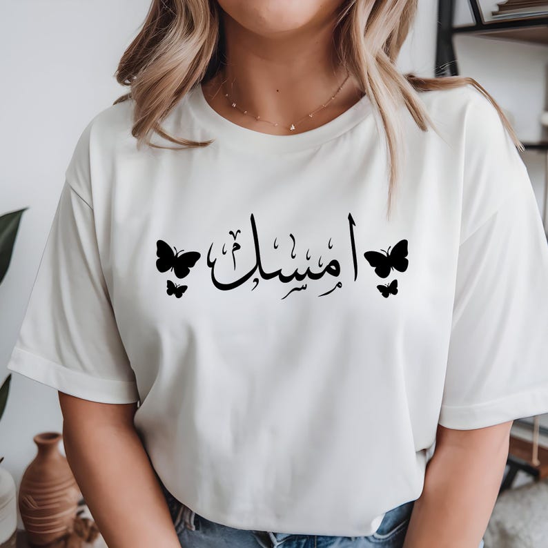 Personalised Arabic Name T Shirt, custom Arabic calligraphy tee, butterfly Arabic shirt, Arabic typography t shirt, personalised Arabic clothing, Islamic fashion top, Muslim women shirt, Arabic script apparel, butterfly graphic tee, custom name t shirt, premium Arabic fashion, personalised Islamic clothing, and custom Arabic text fashion with elegant personalised styling.