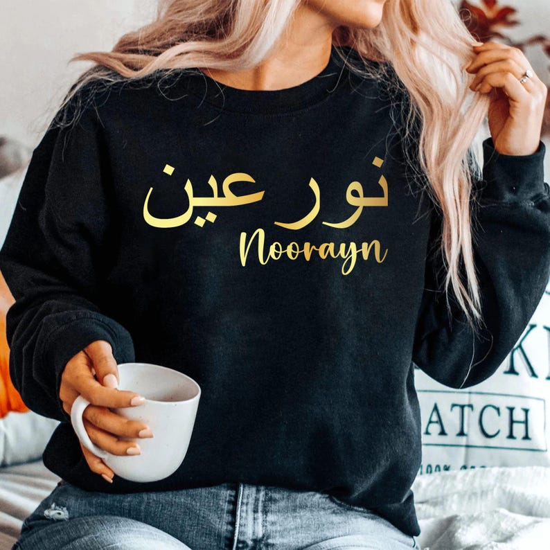 Personalised Arabic Calligraphy Sweatshirt featuring elegant Arabic typography and custom Islamic design. Premium unisex sweatshirt personalised with your chosen Arabic name or text, combining modest fashion, Islamic clothing, and meaningful personalised apparel. Perfect for Muslim women seeking stylish everyday wear, personalised gifts, and faith-inspired fashion suitable for casual outings, family gatherings, Eid celebrations, and special occasions.