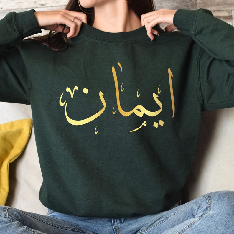Custom Arabic Text Sweatshirt designed for modern modest fashion and comfortable everyday wear. Perfect for Eid celebrations, Ramadan gatherings, family events, travel, university life, shopping trips, casual outings, and relaxed weekends. This personalised sweatshirt combines elegant Arabic typography, premium comfort, and timeless Islamic-inspired styling, making it a fashionable and meaningful addition to any wardrobe.