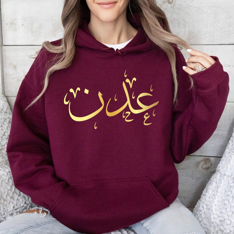 Personalised Arabic Name Hoodie designed for Muslims, Arabic speakers, Islamic fashion lovers, students, family members, friends, and anyone who appreciates meaningful personalised clothing. Featuring a bold Arabic calligraphy name design printed across the chest, this premium hoodie combines cultural identity, personal expression, and modern fashion styling. Perfect for customers searching personalised Arabic clothing, Arabic name apparel, Muslim fashion hoodies, Islamic gifts, custom Arabic typography gar