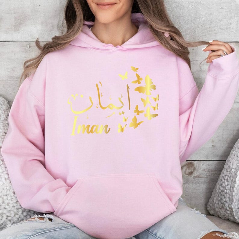 Personalised Arabic Name Butterfly Hoodie combines elegant Arabic typography, feminine butterfly artwork, personalised fashion, and everyday comfort in one stylish garment. Perfect for casual streetwear, modest fashion styling, travel outfits, shopping trips, family gatherings, social occasions, coffee dates, and daily wear. This premium personalised hoodie celebrates culture, identity, beauty, and individuality through meaningful Arabic calligraphy and contemporary fashion design.