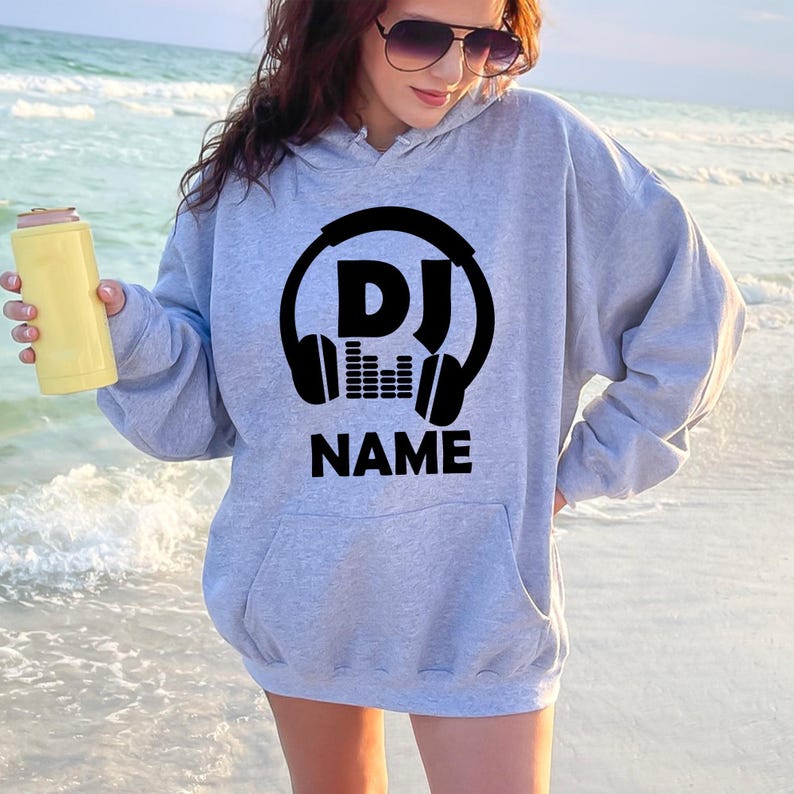 Express your passion for music with this personalised DJ hoodie featuring a custom name and bold headphones design. Whether performing live, creating new mixes, travelling to events or relaxing at home, this premium hoodie offers warmth, comfort and standout style. Every hoodie is proudly printed in the UK by TeezoraPrints.
