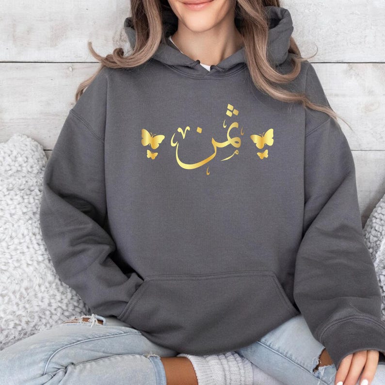 Personalised Arabic Name Butterfly Hoodie featuring premium quality printing, elegant Arabic calligraphy, and beautiful butterfly artwork. Designed to create a meaningful keepsake while providing comfort, warmth, and style, this personalised hoodie makes a thoughtful gift for wives, daughters, sisters, mothers, friends, and loved ones. Combining personalised fashion with timeless Arabic typography, it creates a memorable clothing piece suitable for everyday wear, celebrations, holidays, and personalised gif