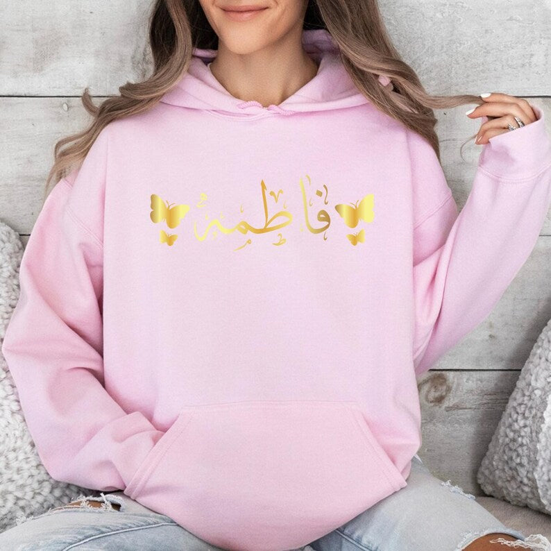 Personalised Arabic Name Butterfly Hoodie designed for Muslim women who appreciate modest fashion, personalised clothing, and elegant Arabic typography. Featuring custom Arabic calligraphy and delicate butterfly artwork, this premium hoodie offers a beautiful blend of comfort, culture, identity, and contemporary fashion. Perfect for everyday wear, family gatherings, Eid celebrations, Ramadan events, university life, travel, casual outings, and meaningful personalised gifting occasions. This stylish personal