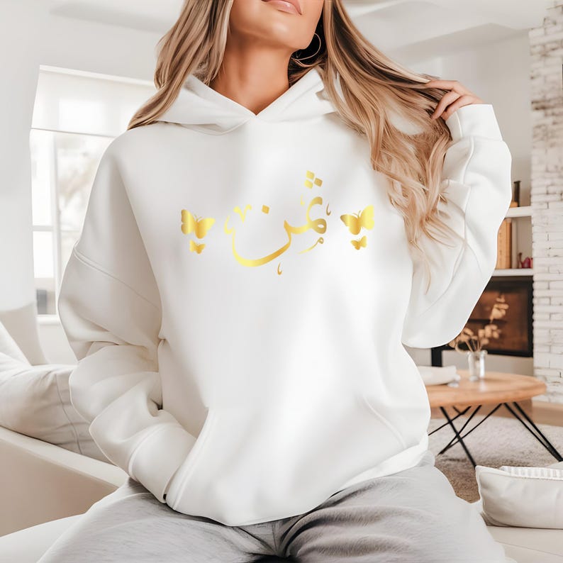 Personalised Arabic Name Butterfly Hoodie designed for Muslim women, Arabic speakers, Islamic fashion lovers, daughters, sisters, mothers, students, and anyone who appreciates meaningful personalised clothing. Featuring elegant Arabic calligraphy combined with delicate butterfly artwork, this premium hoodie offers a stylish blend of modest fashion, personalised design, and cultural expression. Perfect for women searching personalised Arabic hoodies, Islamic gifts for her, Muslim fashion apparel, custom Arab