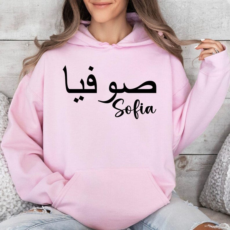 Personalised Arabic Name Hoodie featuring elegant Arabic typography designed to transform your chosen name into a meaningful and stylish piece of wearable art. The combination of flowing Arabic calligraphy and personalised name styling creates a premium garment that celebrates culture, identity, beauty, and individuality. Perfect for customers searching Arabic typography hoodies, personalised Arabic clothing, custom Arabic name apparel, Islamic fashion, and unique personalised gifts.