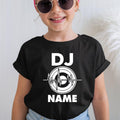A child wearing a black short-sleeve T-shirt with a white 'DJ NAME' graphic on the front, paired with light blue jeans and round sunglasses, against a light indoor background.
