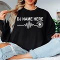 Personalised DJ Name Heartbeat Sweatshirt featuring a custom DJ name, heartbeat waveform and vinyl record graphic. Designed for DJs, music producers, club performers and electronic music lovers, this premium unisex crewneck is professionally printed in the UK by TeezoraPrints for exceptional comfort, warmth and everyday style.