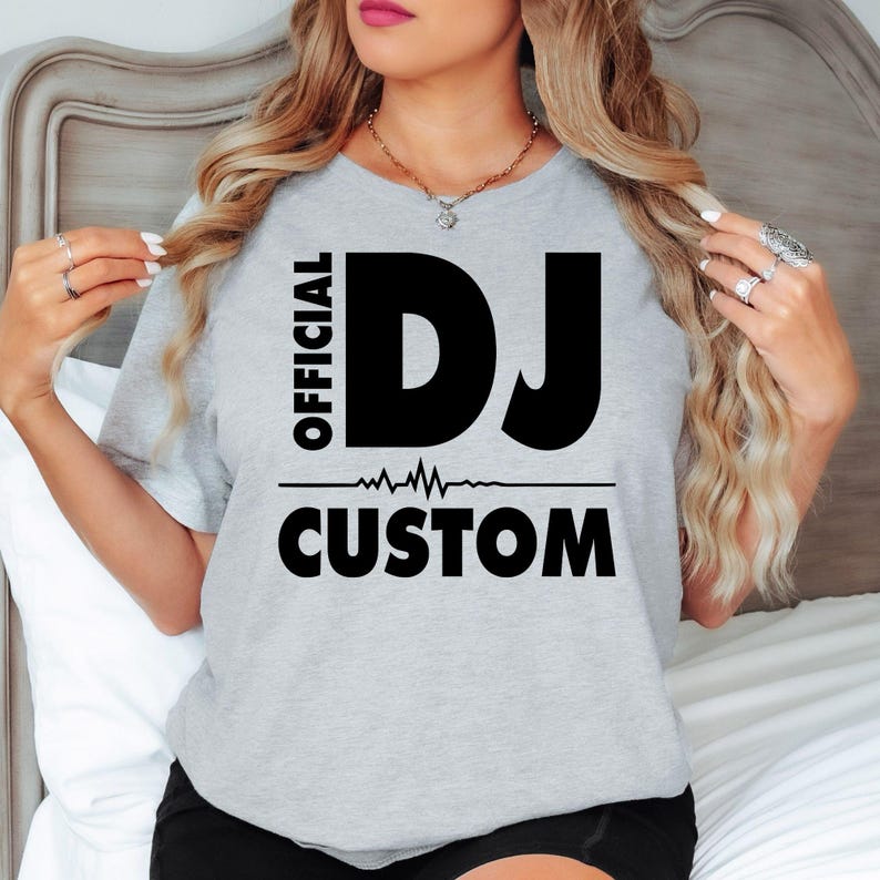 Featuring bold Official DJ typography, a modern heartbeat graphic and personalised name, this premium t-shirt creates a clean professional look for DJs and music enthusiasts. Printed in the UK by TeezoraPrints, this custom design offers lasting quality, vibrant printing and all-day comfort.