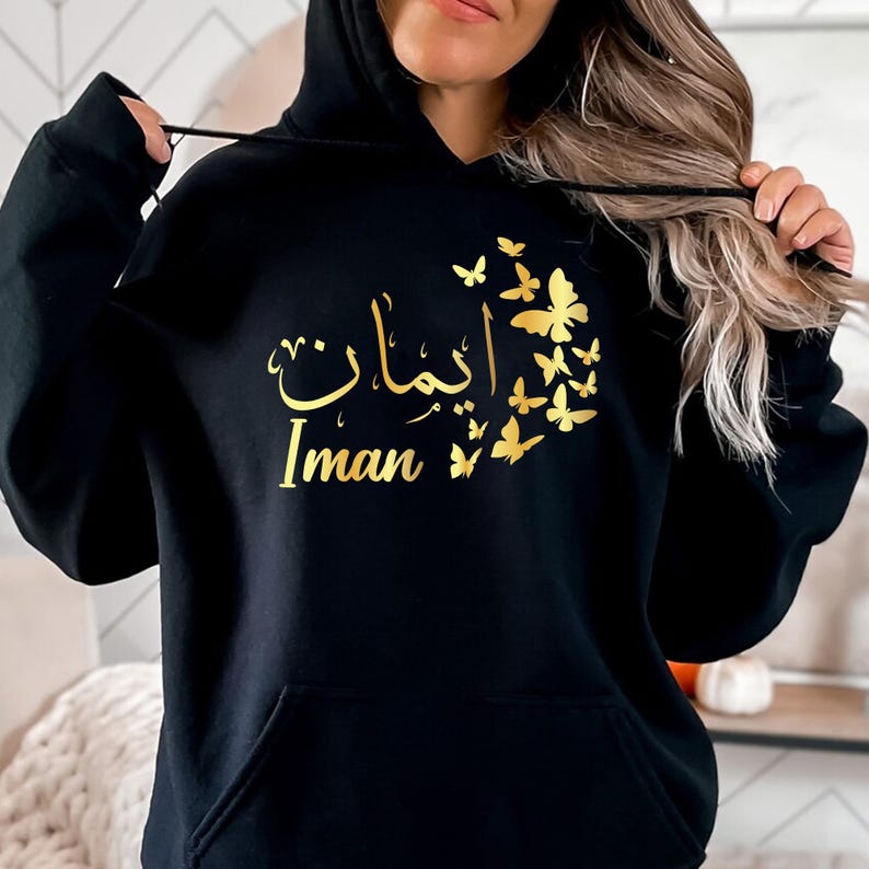 Personalised Arabic Name Butterfly Hoodie designed for Muslim women, Arabic speakers, Islamic fashion lovers, daughters, sisters, mothers, students, and anyone who appreciates meaningful personalised clothing. Featuring elegant Arabic calligraphy combined with delicate butterfly artwork, this premium hoodie offers a stylish blend of modest fashion, personalised design, and cultural expression. Perfect for women searching personalised Arabic hoodies, Islamic clothing, Muslim fashion apparel, and unique custo