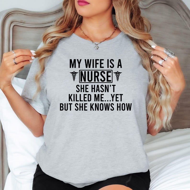 My Wife Is A Nurse She Hasn't Killed Me Yet But She Knows How T Shirt makes a hilarious gift for husbands of nurses, registered nurses, healthcare workers, doctors, medical students, hospital staff, family members, friends, and healthcare professionals. Designed by Teezora Prints, this premium nurse-themed shirt is perfect for birthdays, Christmas, Nurse Appreciation Week, Father's Day, retirement gifts, graduation celebrations, and medical appreciation events.