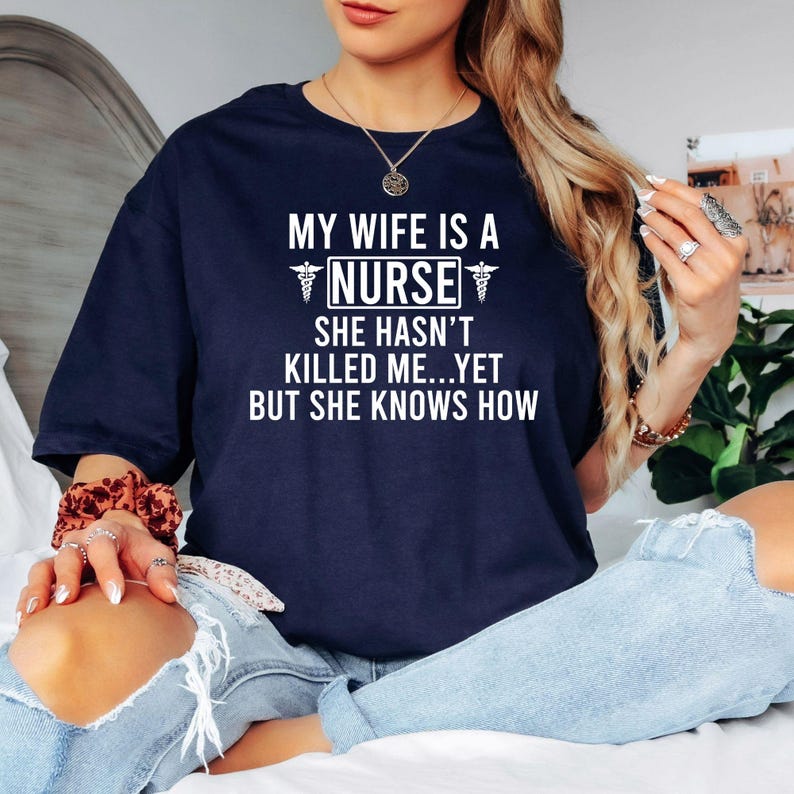 Funny Nurse Shirt, My Wife Is A Nurse Shirt, Nurse Husband Shirt, RN Shirt, Registered Nurse Tee, Nursing Gift, Healthcare Shirt, Medical Shirt, Nurse Life Tee, Hospital Shirt, Funny Medical Shirt, Nurse Family Shirt, RN Gift, Nurse Appreciation Shirt, Premium Graphic T Shirt by Teezora Prints, Nursing Apparel, Medical Humor Tee, Healthcare Clothing, Casual Nurse Fashion, Novelty Nurse Shirt.
