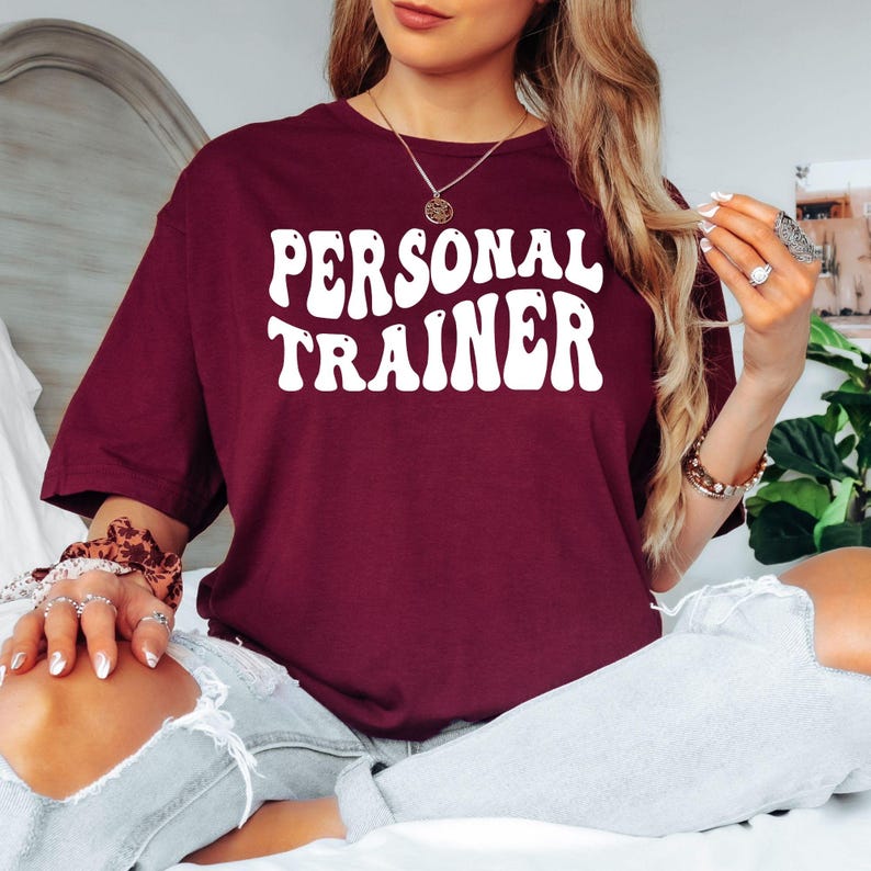Personal Trainer T Shirt featuring bold vintage typography designed for gym instructors, fitness coaches, bodybuilding trainers, and workout professionals. Teezora Prints creates premium fitness apparel for customers searching personal trainer shirts, gym coach clothing, PT t shirts, fitness instructor apparel, workout trainer gifts, bodybuilding fashion, premium gym clothing, athletic lifestyle shirts, and unique trainer graphic tees.