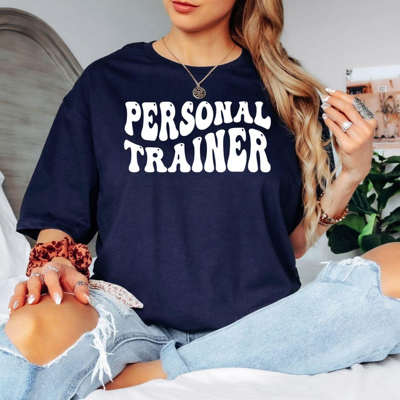 Looking for the perfect gift for a personal trainer or fitness coach? This Personal Trainer T Shirt from Teezora Prints features bold retro typography with a clean professional design that stands out inside and outside the gym. Professionally printed on a premium quality unisex t shirt, it offers exceptional comfort, durability, and everyday style. Perfect for birthdays, Christmas, gym openings, fitness competitions, coach appreciation gifts, and personal trainers who love motivational fitness apparel.