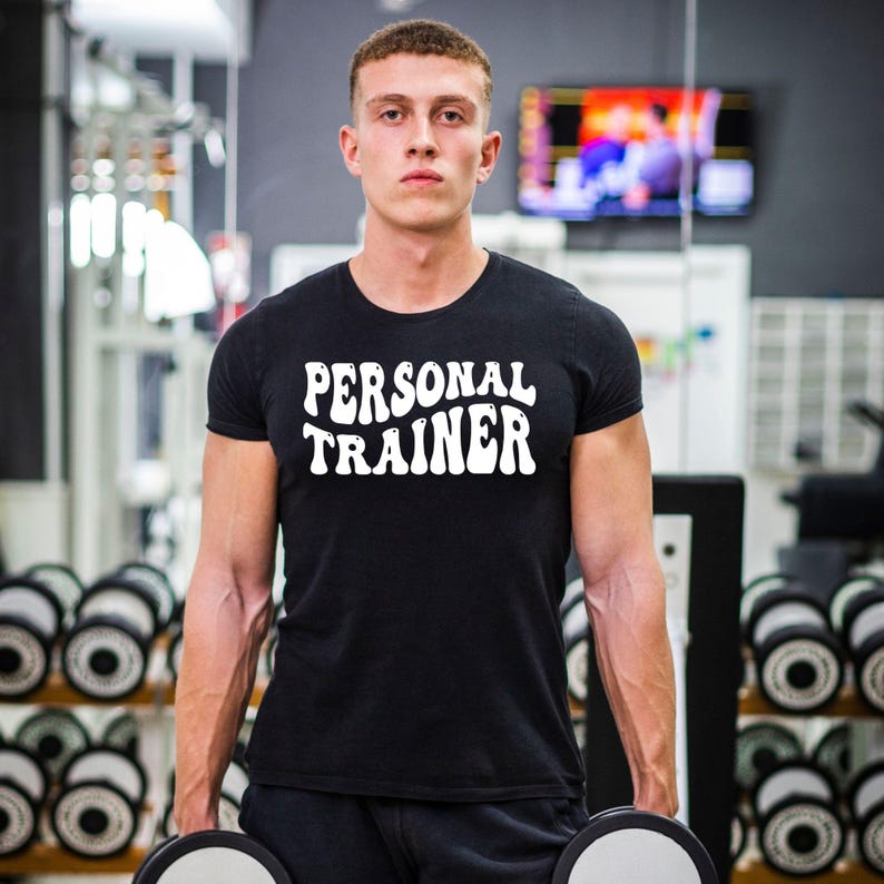 Personal Trainer T Shirt created for certified personal trainers, fitness coaches, gym instructors, strength coaches, wellness professionals, bodybuilding enthusiasts, gym owners, and fitness lovers who inspire others every day. Featuring bold retro typography, this premium graphic tee from Teezora Prints combines exceptional comfort, premium print quality, and stylish athletic fashion, making it ideal for professionals working in gyms, fitness studios, boot camps, and personal training sessions.