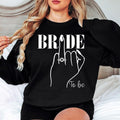 Bride To Be sweatshirt featuring a stylish bridal illustration and elegant engagement ring design, perfect for brides-to-be looking for a fashionable wedding outfit. Ideal for bridal showers, engagement parties, hen weekends, wedding mornings and bridal photoshoots. Every premium sweatshirt is proudly printed in the UK by TeezoraPrints for exceptional comfort and long-lasting quality.