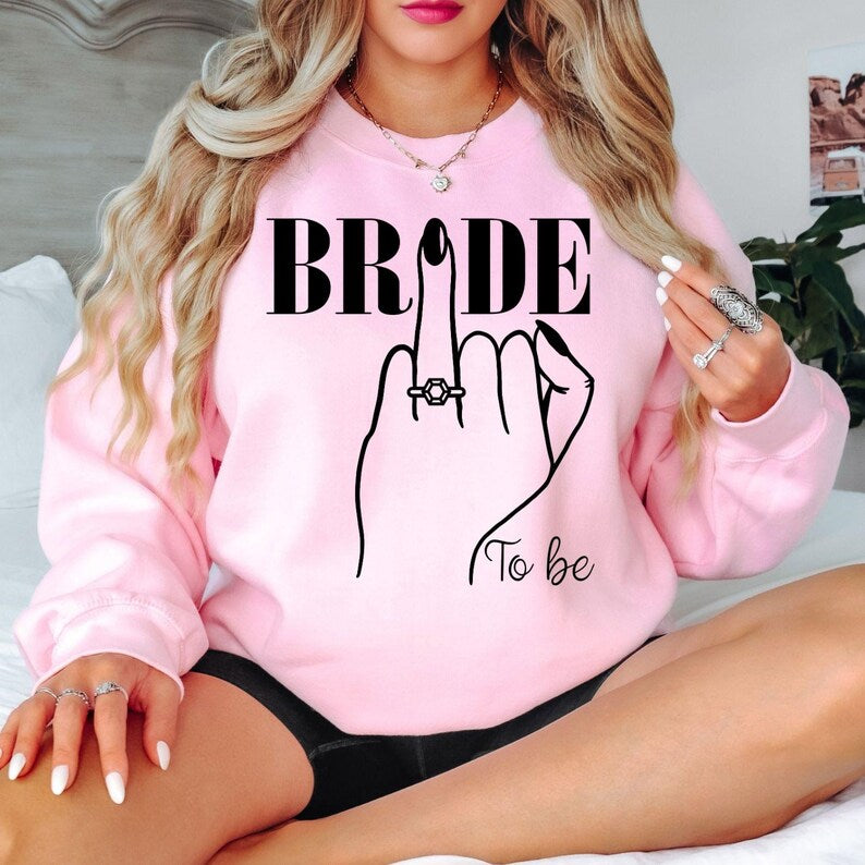 Bride To Be sweatshirt for brides, future wives and newly engaged women. Perfect for engagement parties, bridal showers, hen weekends, wedding mornings, bridal brunches, engagement photoshoots and honeymoon travel. Every premium bridal sweatshirt is professionally printed in the UK by TeezoraPrints with outstanding print quality and lasting comfort.