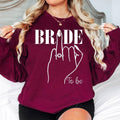 Celebrate your engagement with this elegant Bride To Be sweatshirt featuring a beautiful bridal illustration and sparkling engagement ring artwork. Soft, warm and comfortable, this personalised sweatshirt is perfect for bridal events and everyday wear while planning your wedding. Carefully made to order and printed in the UK by TeezoraPrints for a premium finish.