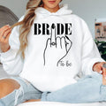 Bride To Be hoodie, personalised bride hoodie, Future Mrs hoodie, engagement hoodie, bridal shower hoodie, wedding morning hoodie, bride gift hoodie, fiancée hoodie, bridal outfit, wedding apparel and cosy engagement clothing. Designed with a modern bridal illustration and professionally printed in the UK by TeezoraPrints for premium quality and everyday wear.