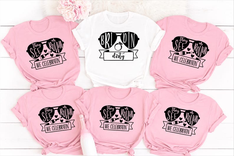 Bride Squad Matching Bachelorette T Shirts created for brides, bridesmaids, maid of honour, bridal party members, and best friends celebrating unforgettable wedding moments together. Featuring the fun "They See Us Rollin' We Celebratin'" design alongside a personalised Bride shirt, this premium matching collection from Teezora Prints is perfect for hen parties, bridal showers, girls' weekends, wedding mornings, group photos, and stylish bridal celebrations with matching outfits.