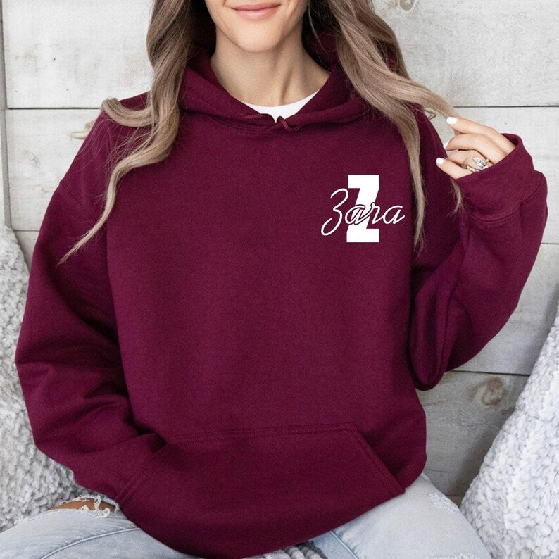 Personalised monogram hoodie customised with your chosen initial and name in a stylish script font. Customers can create a one-of-a-kind hoodie featuring their own name, nickname, family surname or meaningful text. Ideal for personalised fashion, matching family outfits and custom gift giving occasions.