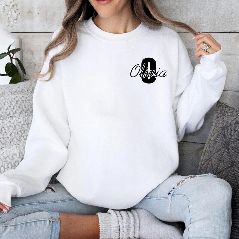 Personalised initial name sweatshirt featuring a custom script letter and personalised name design printed on a premium unisex crewneck sweatshirt. Custom name jumper available in multiple colours and sizes, perfect for everyday wear, personalised fashion lovers, and unique gift giving occasions throughout the year.