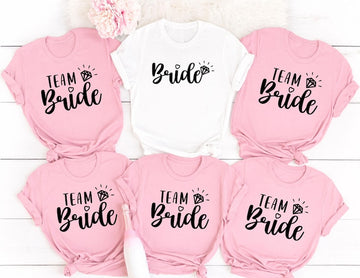 Personalised Team Bride shirt designed for brides, bridesmaids, maid of honour and every member of the bridal party. Featuring elegant script lettering with a sparkling engagement ring, this stylish bridal t-shirt is perfect for creating coordinated wedding outfits and memorable celebrations. Every shirt is professionally printed in the UK by TeezoraPrints using premium cotton for exceptional comfort and long-lasting quality.