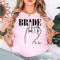 Bride To Be shirt with elegant engagement ring artwork for brides, fiancées and future wives. Ideal for bridal shower outfits, hen party clothing, engagement party shirts, wedding morning apparel, bridal gifts and wedding photoshoots. Every premium t-shirt is proudly printed in the UK by TeezoraPrints with outstanding print quality and comfort.