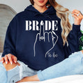 Celebrate your engagement in style with this elegant Bride To Be hoodie featuring a beautiful engagement ring illustration and modern bridal design. Soft, warm and comfortable, it's perfect for wedding planning, relaxing at home or celebrating special moments with loved ones. Every hoodie is made to order and expertly printed in the UK by TeezoraPrints for a premium finish.