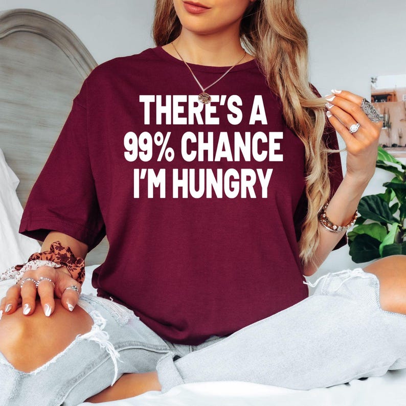 Funny foodie t shirt featuring the quote There's A 99% Chance I'm Hungry in a bold typography design. Perfect for customers searching funny food shirts, hungry quote tees, foodie clothing, burger lover apparel, pizza lover shirts, snack lover gifts, food humour t shirts, brunch outfits, BBQ clothing, novelty foodie fashion, and premium graphic shirts designed for people who are always thinking about food.