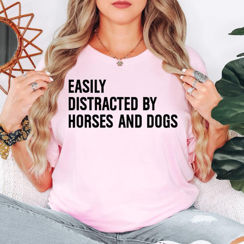 Easily Distracted By Horses And Dogs t shirt is perfect for horse riding lessons, equestrian competitions, dog walks, pet shows, farm visits, stable work, countryside holidays, outdoor adventures, family gatherings, birthdays, weekend outings, animal rescue events, horse club meetings, casual everyday wear, and community festivals. The bold typography design creates a fun conversation starter while proudly celebrating a love for horses, dogs, animals, and the outdoor lifestyle.