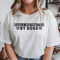 Easily Distracted By Dogs T Shirt featuring a funny dog lover quote, cute paw print design, dog owner apparel, puppy lover shirt, pet lover clothing, animal graphic tee, premium printed fashion, casual everyday wear, humorous typography design, and statement pet apparel. Perfect for customers searching funny dog shirts, dog lover t shirts, dog mum gifts, dog dad clothing, puppy lover apparel, pet owner gifts, animal lover fashion, and premium dog graphic tees.