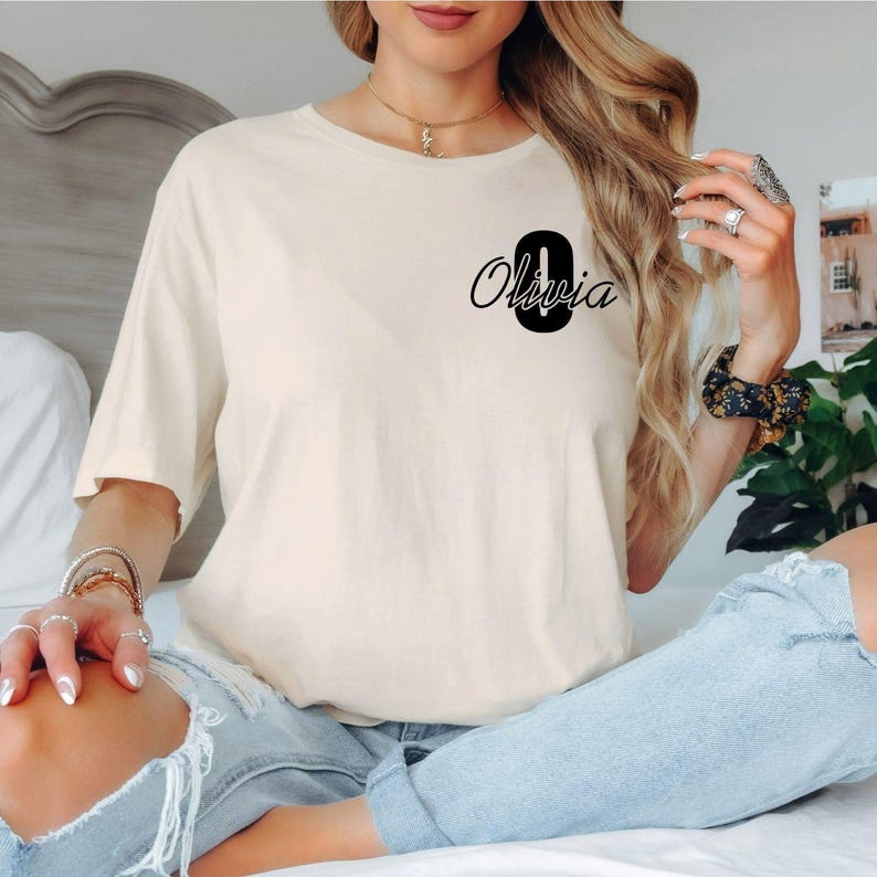 Stylish personalised t shirt featuring a bold monogram initial paired with elegant script typography. This modern personalised design complements jeans, leggings, shorts and casual outfits, creating a fashionable look suitable for everyday wear while offering a premium personalised clothing experience.