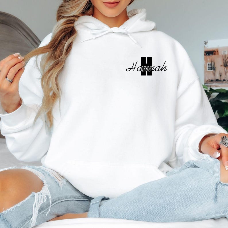 Personalised initial name hoodie featuring a large custom monogram letter combined with an elegant script name printed on the left chest area. This stylish custom hoodie offers a minimalist yet premium appearance, making it perfect for personalised fashion lovers seeking unique custom clothing. Professionally printed in the UK using durable high quality printing methods.