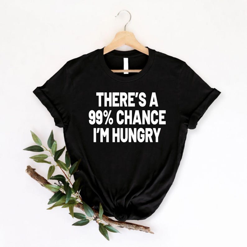 There's A 99% Chance I'm Hungry t shirt created for food lovers, foodies, snack enthusiasts, burger fans, pizza lovers, takeaway addicts, coffee drinkers, dessert lovers, students, parents, chefs, and anyone who jokes that they are always hungry. This premium graphic tee features bold typography with a humorous statement that perfectly matches everyday foodie life while providing exceptional comfort, premium print quality, and stylish casual fashion for every occasion.