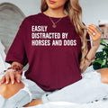 Funny horse and dog lover t shirt featuring the quote Easily Distracted By Horses And Dogs in a clean typography design created for equestrians, riders, pet owners, and animal enthusiasts. Perfect for customers searching horse lover shirts, dog lover clothing, equestrian graphic tees, funny pet apparel, horse riding shirts, stable clothing, farm life fashion, horse mum gifts, dog mum shirts, premium animal lover clothing, and unique everyday graphic t shirts.
