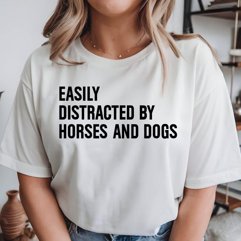 Easily Distracted By Horses And Dogs t shirt created for horse lovers, dog lovers, equestrians, riders, pet parents, animal rescuers, stable owners, trainers, veterinarians, farm life enthusiasts, and anyone whose day instantly gets better after seeing a horse or a dog. Featuring a bold typography design with a playful statement, this premium graphic tee perfectly reflects an animal lover's personality while offering exceptional comfort, durable print quality, stylish everyday fashion, and a fun conversatio
