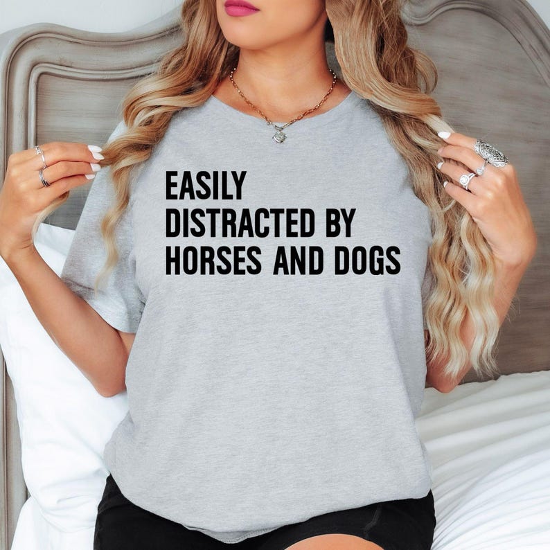 Easily Distracted By Horses And Dogs t shirt makes a thoughtful gift for horse mums, horse dads, dog mums, dog dads, equestrians, stable owners, riders, veterinarians, pet groomers, trainers, animal rescuers, family members, friends, and anyone who adores horses and dogs. This premium graphic shirt is ideal for birthdays, Christmas, Mother's Day, Father's Day, horse competitions, pet adoption celebrations, riding club events, and unforgettable gifts for passionate animal lovers.