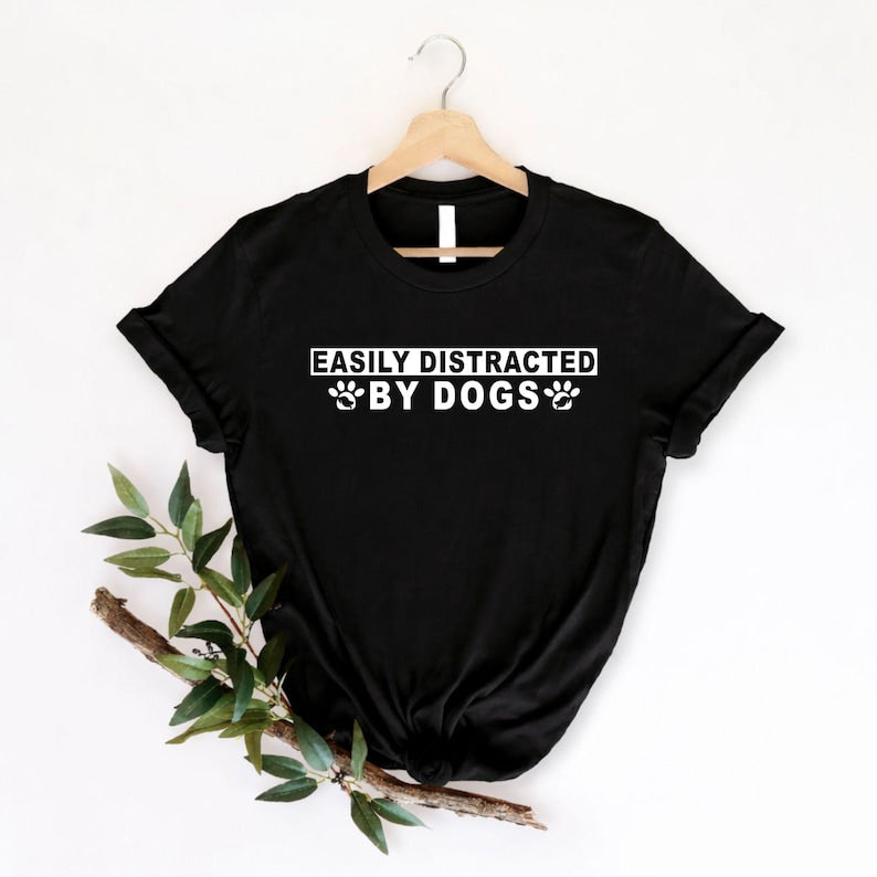 Looking for the perfect gift for someone completely obsessed with dogs? This Easily Distracted By Dogs t shirt features a bold typography design with adorable paw prints that instantly captures every dog lover's personality. Professionally printed on a premium quality unisex t shirt, it offers superior comfort, lasting durability, and everyday style. An excellent gift for birthdays, Christmas, Mother's Day, Father's Day, pet adoption celebrations, dog walking adventures, and anyone who proudly calls themsel